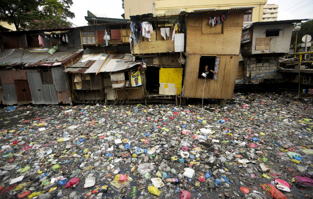 A Filipino informal settler is seen inside a shanty dwelling along a polluted river in Manila, Philippines, May 6, 2014. According to the latest survey of the Social Weather Stations (SWS), 11.5 million Filipino households or 53 per cent of the survey respondents defined themselves as poor. (Photo by Ritchie B. Tongo/EPA)