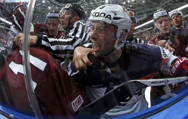 Tyler Johnson of the U.S. (C) fights with Latvia's Kristaps Sotniekis (11) during the second period of their men's ice hockey World Championship Group B game at Minsk Arena in Minsk May 15, 2014. Picture taken with a fisheye lens. (Photo by Alexander Demianchuk/Reuters)
