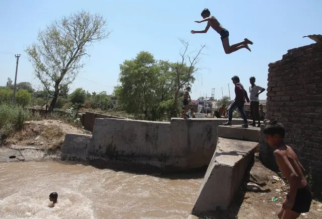Children jump into a water canal to cool themselves on a hot summer day in Jammu, India, on May 15, 2016. Much of India has been suffering from an intense heat wave for weeks. (Photo by Channi Anand/AP Photo)