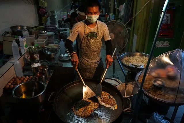 This photo taken on April 17, 2017 shows a man making food at a street stall in the Phrakanong district of Bangkok, Thailand. Street food stalls will be banned from all of Bangkok's main roads under a clean-up crusade, a city hall official said Tuesday, prompting outcry and anguish in a food-obsessed capital famed for its spicey roadside cuisine. (Photo by Lillian Suwanrumpha/AFP Photo)