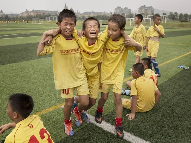 Football players help an injured player off the field during training at the Evergrande International Football School near Qingyuan in Guangdong Province. (Photo by Kevin Frayer/Getty Images)