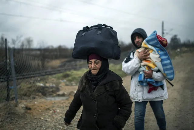 A woman balances a bag on ther head and a man carries a child as migrants and refugees make their way across the Macedonia-Serbia border at Tabanovce, on February 4, 2016. More than a million people headed to Europe in search of new lives last year, most of them refugees fleeing conflict in Syria, Iraq and Afghanistan in the continent's worst migration crisis since World War II. The onset of winter does not appear to have deterred the migrants. (Photo by Robert Atanasovski/AFP Photo)