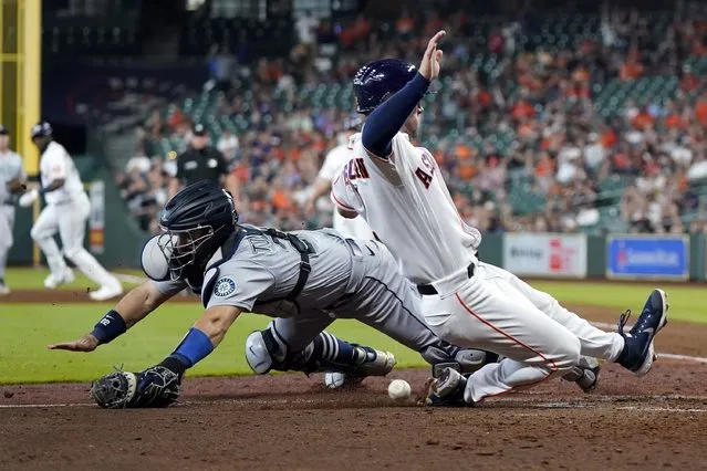 Seattle Mariners catcher Luis Torrens, left, reaches for the ball as Houston Astros' Alex Bregman scores during the sixth inning of a baseball game Wednesday, May 4, 2022, in Houston. (Photo by David J. Phillip/AP Photo)