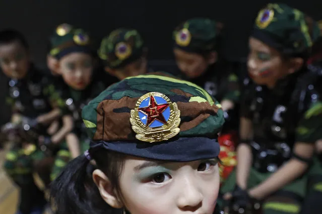 In this Friday, June 23, 2017 photo, a kindergarten child wears a military costume with a PLA badge as she prepares at backstage with her schoolmates for a performance during a graduation ceremony in Beijing. (Photo by Andy Wong/AP Photo)