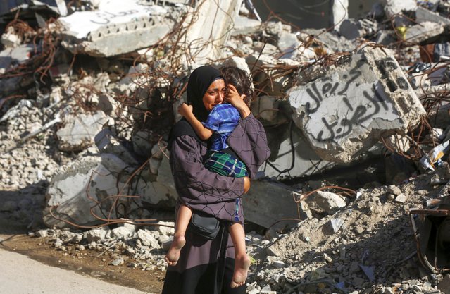 A Palestinian woman carrying her child in her arms cries in front of a collapsed building as the dead bodies of Palestinians who died in Israel's attack on the Bureij Refugee Camp brought to the al-Awda Hospital for burial in Gaza City, Gaza on September 19, 2024. It was reported that there were dead and injured people as a result of the attack carried out by the Israeli army. (Photo by Ashraf Amra/Anadolu via Getty Images)