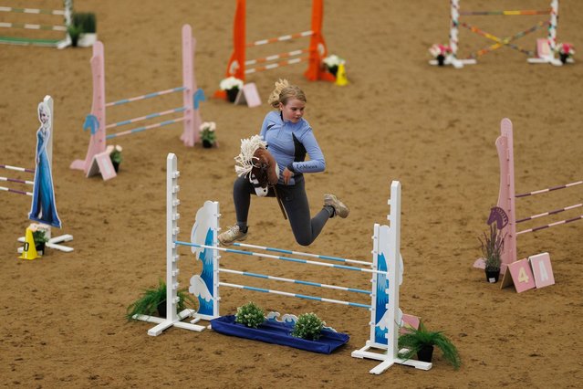 Competitors take part in the UK Hobby Horse championship at Bury Farm Equestrian Centre on September 08, 2024 in Slapton, United Kingdom. While hobby horsing as a form of play has been around for centuries, the modern-day interpretation of the sport originated in Finland. Hobby horse competitions feature young enthusiasts trotting, galloping, and cantering on toy horses in various disciplines such as jumping and dressage. Its popularity has surged in recent years, especially during covid, and is growing in appeal. Young equine enthusiasts take advantage of its inclusivity, and enjoy the physical activity required, creativity and freedom of expression. The sport has also been found to help young people suffering with autism and ADHD, giving them a chance to connect with other young people with a love of horses. (Photo by Dan Kitwood/Getty Images)