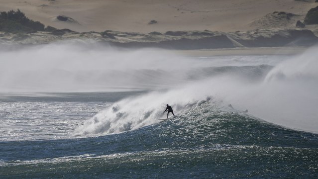 A surfer rides a wave at One Mile Beach at Port Stephens, Australia, Sunday, June 12, 2022. (Photo by Mark Baker/AP Photo)