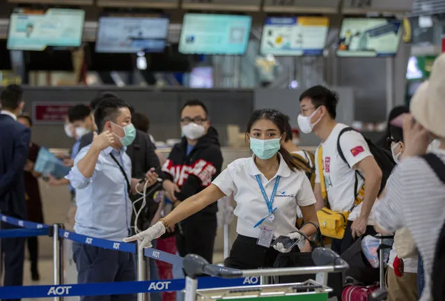 An airline staffer assists tourists from Wuhan, china, as they wait for a charter flight back to Wuhan at the Suvarnabhumi airport, Bangkok, Thailand, Friday, January 31, 2020. A group of Chinese tourists who have been trapped in Thailand since Wuhan was locked down due to an outbreak of new virus returned to China on Friday. (Photo by Gemunu Amarasinghe/AP Photo)