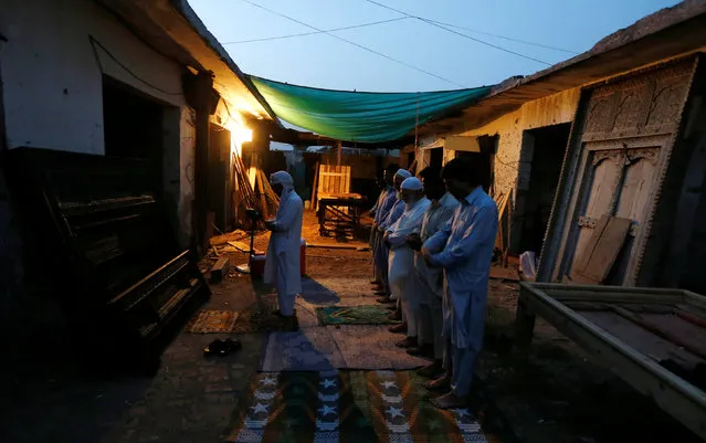 Workers and neighbours of a carpentry workshop pray after breaking their fast during the holy month of Ramadan in Islamabad, Pakistan June 11, 2016. (Photo by Caren Firouz/Reuters)