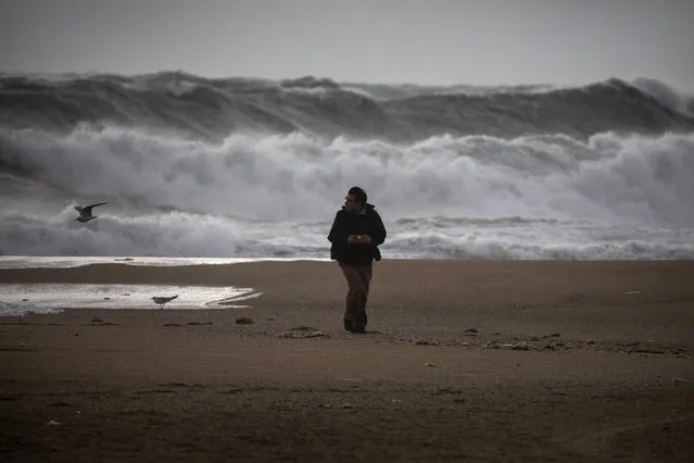 A man walks at the beach during strong winds in Barcelona, Spain, Monday, January 20, 2020. Two people have died as storms carrying heavy snowfalls and gale-force winds lashed many parts of Spain on Monday. The storm has forced the closure of Alicante airport and some 30 roads in eastern region. Six provinces are on top alert. (Photo by Emilio Morenatti/AP Photo)
