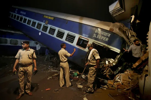 Indian policemen stand guard near the upturned coaches of the Kalinga-Utkal Express after an accident near Khatauli, in the northern Indian state of Uttar Pradesh, India, Sunday, August 20, 2017. Several coaches of a passenger train derailed, causing fatalities and injuries in northern India on Saturday, officials said. (Photo by Altaf Qadri/AP Photo)
