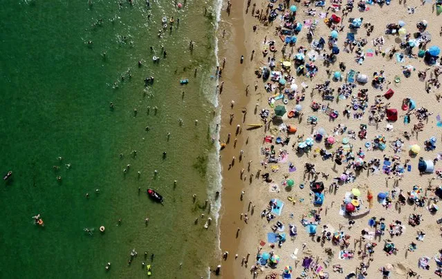 People and children enjoy the hot weather at Bournemouth Beach, as a heatwave reaches the country, in Bournemouth, Britain, June 17, 2022. (Photo by Hannah McKay/Reuters)