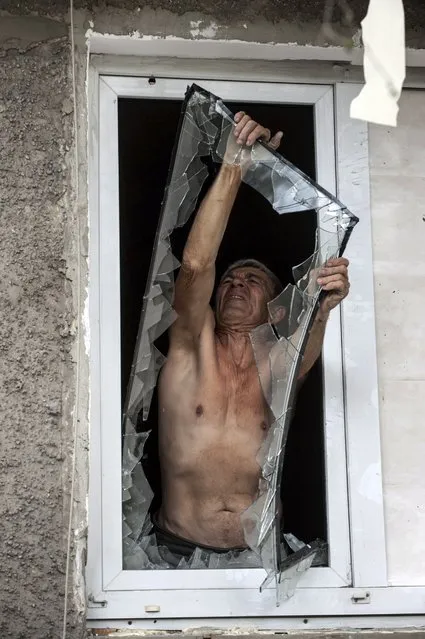 A local resident takes off a broken window in his flat in a damaged building after shelling, during fighting between pro-Russian rebels and Ukrainian government forces in Shakhtarsk, Donetsk region, eastern Ukraine, Thursday, Aug. 7, 2014. (Photo by Evgeniy Maloletka/AP Photo)