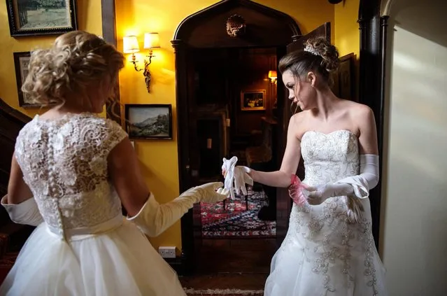 Debutante Olivia Mott, 20, from Charlottesville, Virginia (L) passes Callan Foran (R), 20, from Ohio a pair of white gloves as they prepare at Boughton Monchelsea Place ahead of the Queen Charlotte's Ball on September 9, 2017 in Maidstone, England. (Photo by Jack Taylor/Getty Images)