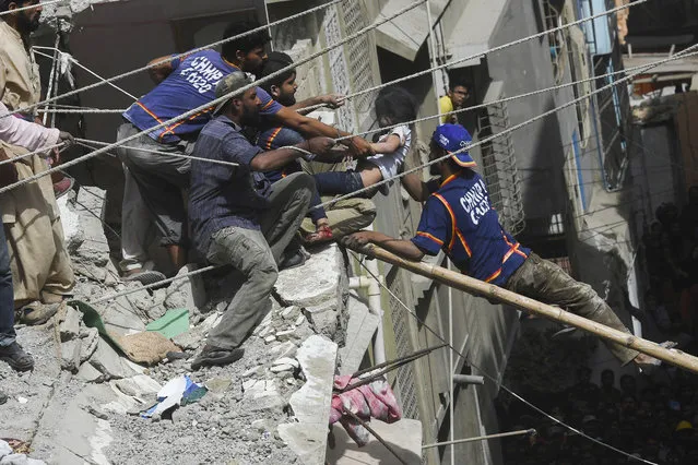Pakistani volunteers rescue an injured girl from the rubble of a collapsed five-story residential building in Karachi on March 5, 2020. (Photo by Asif Hassan/AFP Photo)