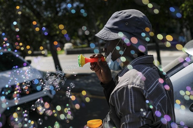 Haitian migrant Philippe hawks bubble blower guns on one of the most congested avenues of Santo Domingo, Dominican Republic, Tuesday, November 23, 2021. (Photo by Matias Delacroix/AP Photo)