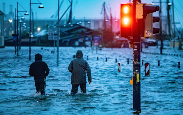 People make their way across a flooded street in Flensburg, norhtern Germany on October 20, 2023 as Storm Babet caused havoc. (Photo by Axel Heimken/AFP Photo)