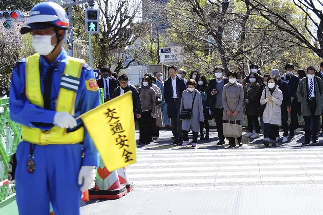 People wearing a protective face mask wait at a pedestrian crossing Thursday, April 2, 2020, in Tokyo. (Photo by Eugene Hoshiko/AP Photo)