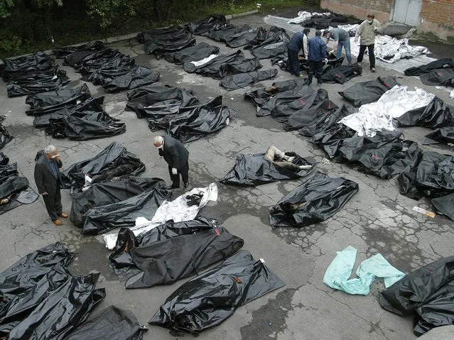 People try to identify their relatives among the bodies of Beslan hostage crisis' victims 05 September 2004, in the yard of the morgue in Vladikavkaz. The first funerals for the hundreds killed in the Russian hostage siege took place in Beslan Sunday, an AFP correspondent reported. Some 338 people were killed as a result of the three- day school siege in southern Russia, the RIA- Novosti agency quoted the spokesman for the regional president as saying on Sunday. (Photo by Viktor Drachev/AFP Photo)