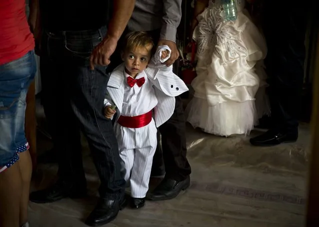 A Romanian Roma child waits in line to pass under a table, part of a local tradition, during a religious service celebrating the Birth of the Virgin Mary at the Bistrita Monastery in Costesti, Romania, Monday, September 8, 2014. (Photo by Vadim Ghirda/AP Photo)