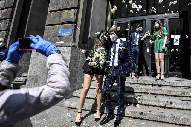 A just married couple is celebrated by friends as they leave the registry offices after the civil ceremony in Milan, Italy, Friday, May 8, 2020. The municipality of Milan restarted celebrating civil marriages Thursday, as the city is slowly returning to life after the long shutdown due to the coronavirus outbreak. Access to the ceremony is only allowed for best men. (Photo by Claudio Furlan/LaPresse via AP Photo)