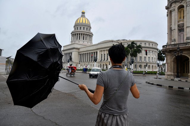 A tourist from China tries to hold his umbrella as Hurricane Rafael passes by Havana, Cuba, on November 6, 2024. (Photo by Norlys Perez/Reuters)