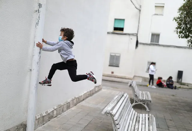 Kilian, 6, wears a protective face mask as he jumps from a bench, after restrictions were partially lifted for children, during the coronavirus disease (COVID-19) outbreak, in Igualada, Spain on April 26, 2020. (Photo by Nacho Doce/Reuters)
