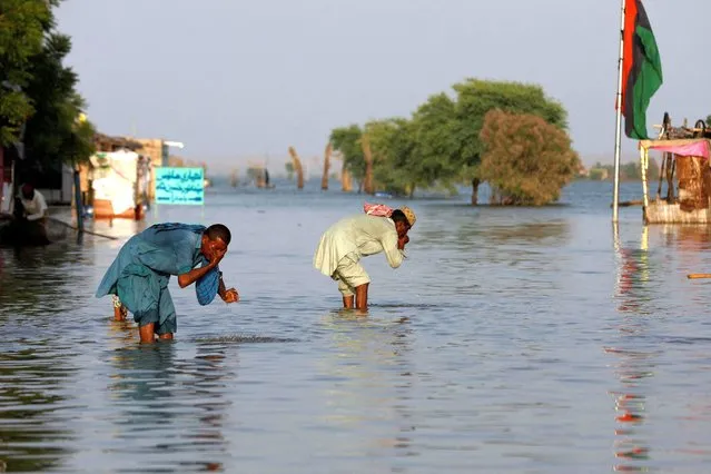 Men perform ablution with the flood water in Bajara village, at the banks of Manchar lake, in Sehwan, Pakistan on September 6, 2022. (Photo by Akhtar Soomro/Reuters)