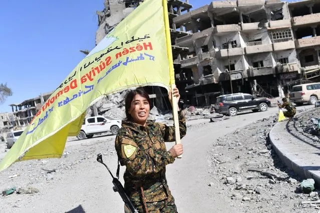 Rojda Felat, a Syrian Democratic Forces (SDF) commander, waves her group' s flag at the iconic Al- Naim square in Raqa on October 17, 2017. US- backed forces said they had taken full control of Raqa from the Islamic State group, defeating the last jihadist holdouts in the de facto Syrian capital of their now- shattered “caliphate”. (Photo by Bulent Kilic/AFP Photo)