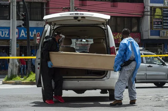 Officials carry a dead body of a woman in a coffin suspected of coronavirus (Covid-19) in Quito, Ecuador on May 14, 2020. Mayor of Quito Jorge Yunda denied and confirms that the death was due to respiratory problems. (Photo by Josep Vecino/Anadolu Agency via Getty Images)