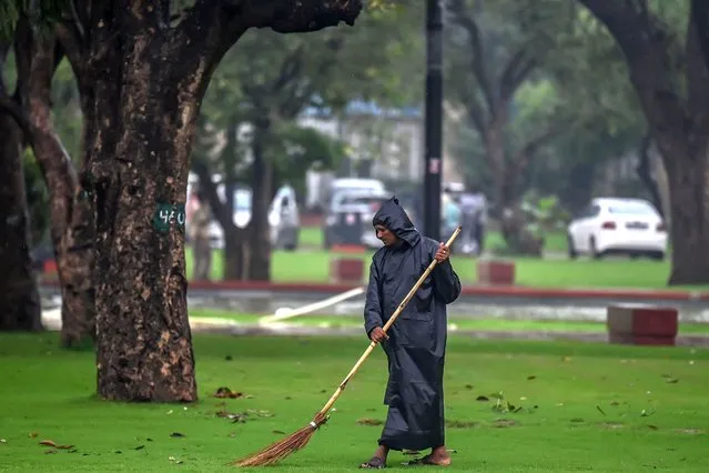A worker sweeps the grass near the newly inaugurated central vista project during a rainfall in New Delhi in September 23, 2022. (Photo by Money Sharma/AFP Photo)
