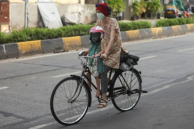 A woman rides a bicycle carrying a child after some restrictions were lifted during a nationwide lockdown to slow the spread of the coronavirus disease (COVID-19), in Mumbai, India, June 8, 2020. (Photo by Francis Mascarenhas/Reuters)