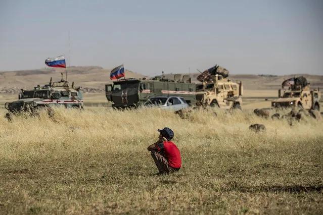 A Syrian boy looks at Russian and US military vehicles in the northeastern Syrian town of al-Malikiyah (Derik) at the border with Turkey, on June 3, 2020. (Photo by Delil Souleiman/AFP Photo)