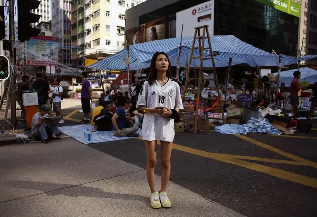 Crystal, 15, a part-time boutique sales assistant, poses on Nathan Road in Mongkok shopping district in Hong Kong October 7, 2014. Holding a walkie talkie for fast communication with other supporters, Crystal said, “I am not demanding Chief Executive Leung Chun-ying to quit, but (want) to protect protesters from being threatened badly by opponents and the police”. (Photo by Bobby Yip/Reuters)
