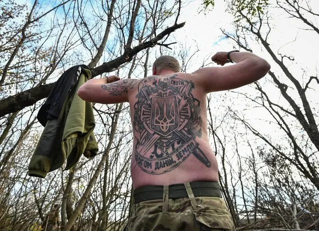 A serviceman shows his tattoo at his position on a front line in Zaporizhzhia region, Ukraine on November 3, 2022. The inscription on the tattoo says “I live on my God-given land”. (Photo by Reuters/Stringer)