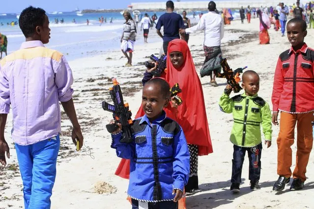 Somali children stroll along the beach holding toy guns during the Muslim festival of Eid-al-Adha in capital Mogadishu October 4, 2014. Muslims around the world celebrate Eid al-Adha to mark the end of the haj pilgrimage by slaughtering sheep, goats, camels and cows to commemorate Prophet Abraham's willingness sacrifice his son, Ismail, on God's command. (Photo by Omar Faruk/Reuters)