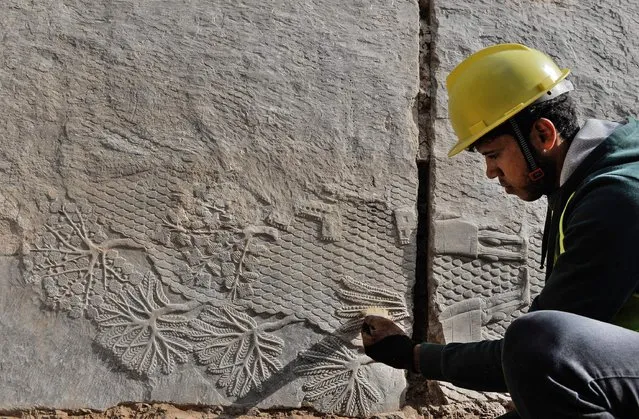 An Iraqi worker excavates a rock-carving relief recently found at the Mashki Gate, one of the monumental gates to the ancient Assyrian city of Nineveh, on the outskirts of what is today the northern Iraqi city of Mosul on October 19, 2022. (Photo by Zaid Al-Obeidi/AFP Photo)