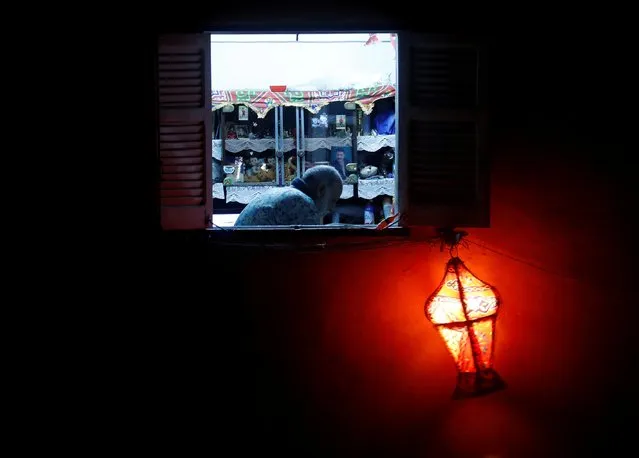 A man reads the Koran, seen from a window of his house decorated with a traditional Ramadan lantern called “fanous”, on the Laylat al-Qadr, or Night of Power, the holiest night for Muslims, during a night-time curfew amid the spread of the coronavirus disease (COVID-19) in Cairo, Egypt May 19, 2020. (Photo by Amr Abdallah Dalsh/Reuters)