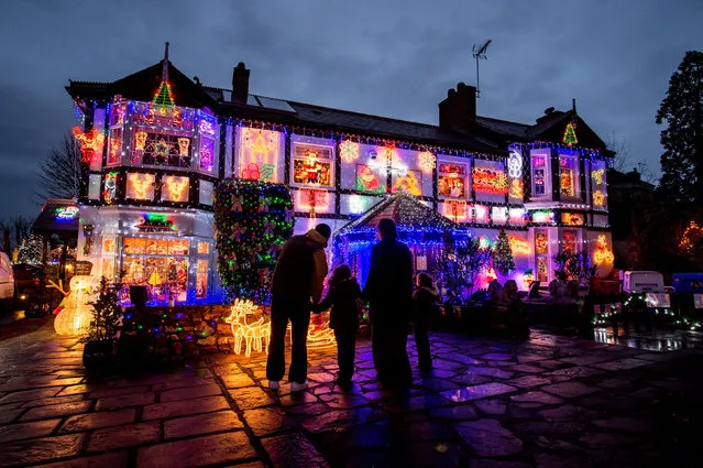 Families admire the festive decorations on Sheila and John Gill’s house in Stow Hill, Newport. Every year, the couple open up their home to visitors over the festive season. This year, the pair began hanging decorations and fixing thousands of lights in late August. Visitors are asked to donate £2 as the couple try to raise thousands of pounds for various good causes. The display will be switched on from 4pm-8pm every day until 31 December. (Photo by Ben Birchall/PA Wire)