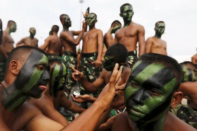 Indonesian soldiers help each other to apply camouflage paint before a rehearsal for the ceremony marking the 70th anniversary of Indonesia's military in Cilegon, Banten province, October 3, 2015. (Photo by Reuters/Beawiharta)