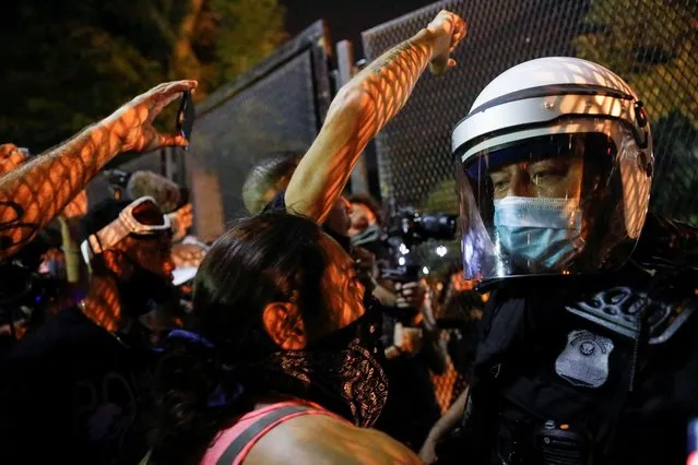 Demonstrators face off with a security officer near a fence around the White House during a protest in Washington, August 27, 2020. (Photo by Andrew Kelly/Reuters)