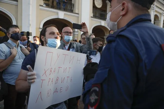 A protester stands in front of a police officer holding a poster reading “Putin stop poisoning people!” during a picket in support of Russian opposition leader Alexei Navalny in the center of St. Petersburg, Russia, Thursday, August 20, 2020. Russian opposition politician Alexei Navalny is on a hospital ventilator in a coma, after falling ill from a suspected poisoning, according to his spokeswoman Kira Yarmysh. (Photo by Elena Ignatyeva/AP Photo)