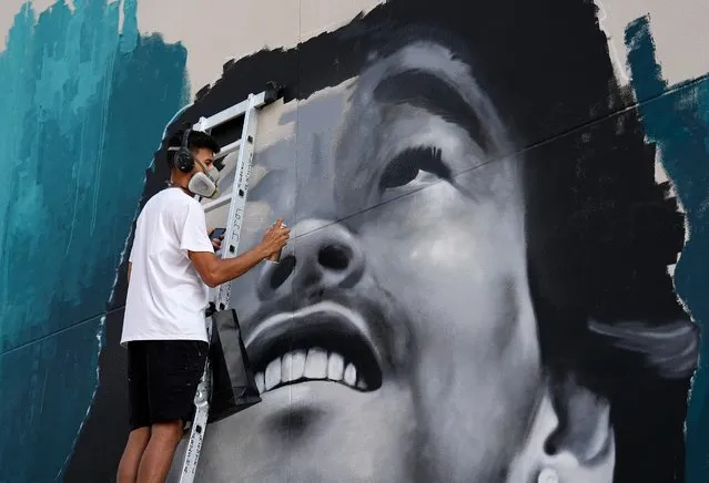 A man is painting the picture of former soccer player Ronaldinho of Brazil on a wall on the day before the start of the Soccer World Cup in Doha, Qatar, Saturday, November 19, 2022. (Photo by Martin Meissner/AP Photo)