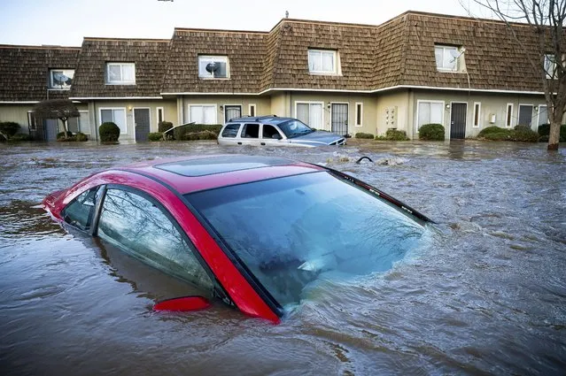Floodwaters course through a neighborhood in Merced, Calif., on Tuesday, January 10, 2023. Following days of rain, Bear Creek overflowed its banks leaving dozens of homes and vehicles surrounded by floodwaters. (Photo by Noah Berger/AP Photo)