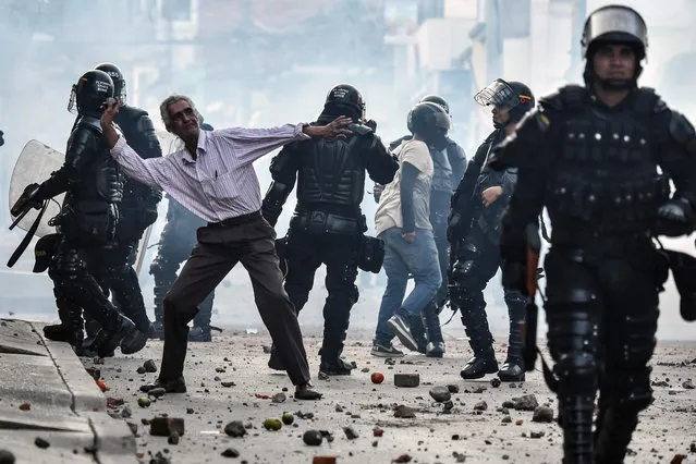 A demonstrator throws stones during a protest against a campaign rally held for Rodrigo Londono Echeverri, known as “Timochenko”, the presidential candidate for the Common Alternative Revolutionary Force (FARC) political party, who was to hold a campaign meeting during his visit to the municipality of Yumbo, Colombia, on February 7, 2018 but was forced to leave because protesters were throwing stones. (Photo by Luis Robayo/AFP Photo)