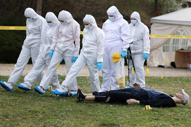 Students of the CY Forensic school takes photograph and walk on a crime scene reconstruction during a training session in Neuville-sur-Oise, northeast of Paris, on March 21, 2025. CY Forensic School, part of CY Cergy Paris University, accommodates 20 students per year who learn the technical and scientific prerequisits of forensic police investigative work, with hands-on exercises nearing real-life scenarios. (Photo by Alain Jocard/AFP Photo)