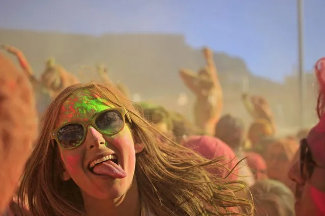 A woman react inside a cloud of paint powder during the holi one colour Festival held in the city of Cape Town, South Africa, Saturday, March 2, 2013. Thousands of people are taking part in the festival by throwing coloured paint powder at each other to express freedom and the colour of everyday life. (Photo by Schalk van Zuydam/AP Photo)