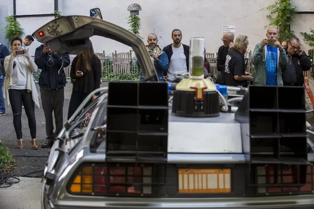 Pedestrians stop to look at and photograph a DeLorean Motor Company DMC-12 customized to look identical to the car used in the film "Back to the Future Part II" and that will be part of a Lyft promotion in New York, October 21, 2015. (Photo by Lucas Jackson/Reuters)