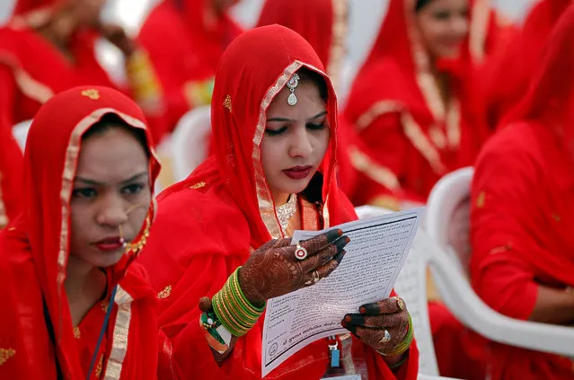 A bride reads a pamphlet before taking her wedding vow during a mass marriage ceremony in which, according to its organisers, 70 Muslim couples took their wedding vows, in Ahmedabad, India, February 11, 2018. (Photo by Amit Dave/Reuters)