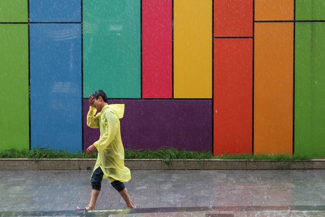 A person wears rain coat while walking on a street during heavy rain and high winds, after Tropical Storm Co-May made landfall in a nearby city, in Shanghai, China on July 30, 2025. (Photo by Go Nakamura/Reuters)